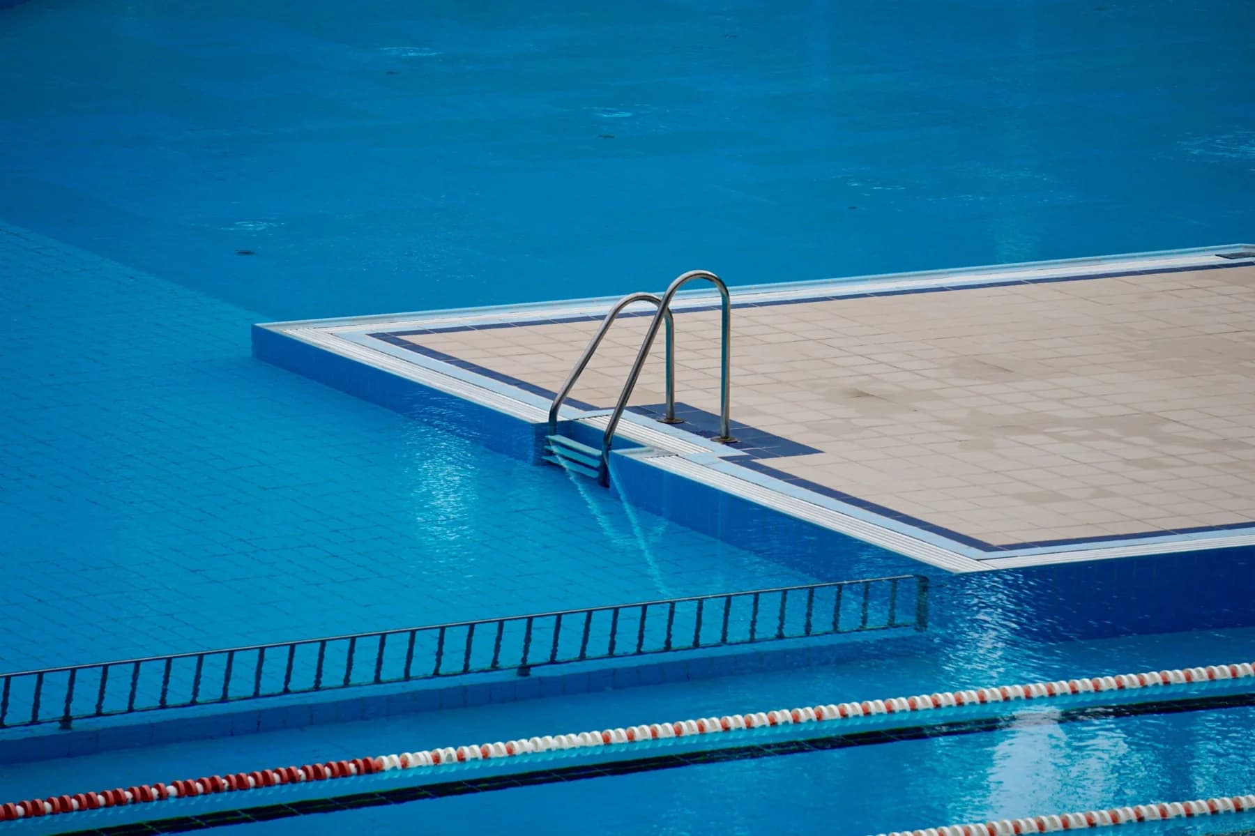 A tiled swimming pool with its steps and lane ropes