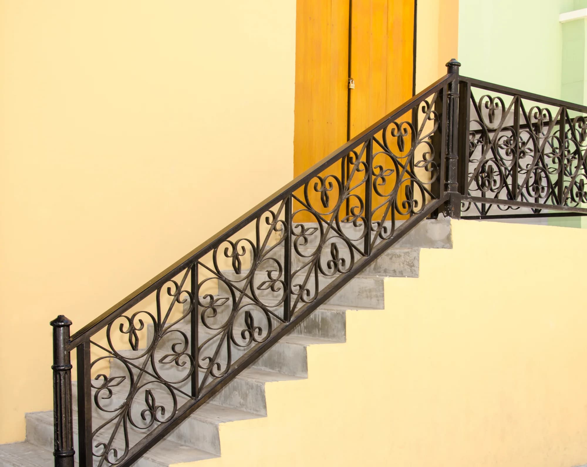 Painted wrought-iron stair railing beside a wooden door