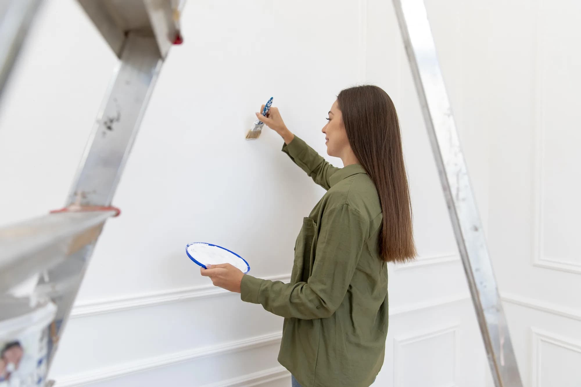 Woman painting a white wall with a brush