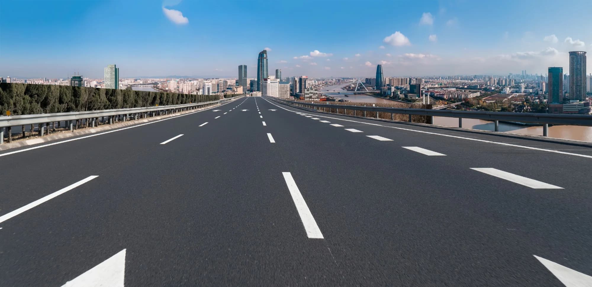 A marked highway leading to a riverside city skyline